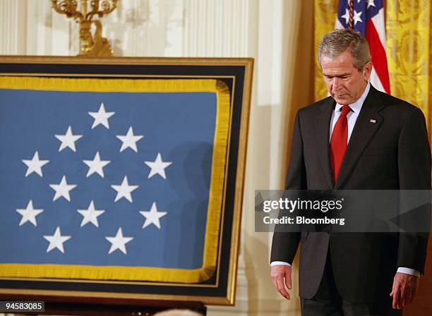 President George W. Bush bows his head in prayer during the invocation ceremony for a Medal of Honor presentation for the late Marine Corporal Jason...