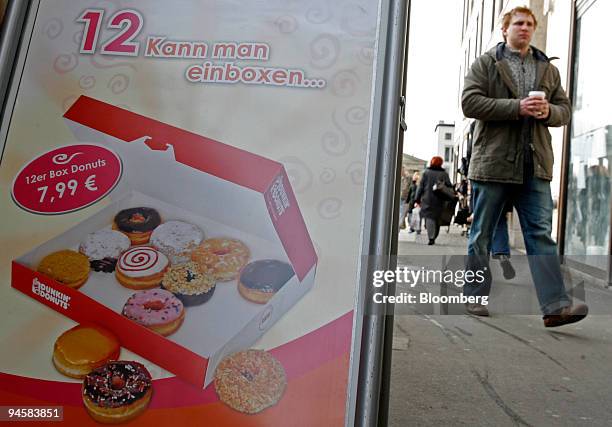 Starbucks customer passes a Dunkin' Donuts shop with a cup of Starbucks coffee in Berlin, Germany, Wednesday, Jan. 31, 2007. Starbucks pushed maple...