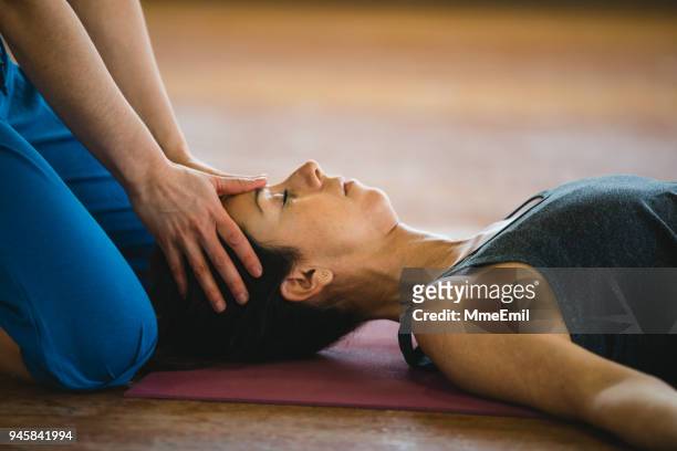 mujeres practicando la posición de yoga y masaje de la cabeza. postura de shavasana o cadáver - head massage fotografías e imágenes de stock