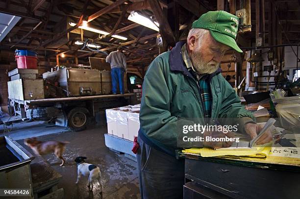 Dennis Fender notes a customer's order at his makeshift desk atop one of the holding tanks at Fender's Fish Farm Monday, Nov. 6 near Baltic, Ohio, as...