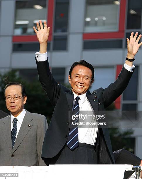 Yasuo Fukuda, former chief cabinet secretary of Japan, left, smiles as Taro Aso, secretary general of the Liberal Democratic Party , waves during...