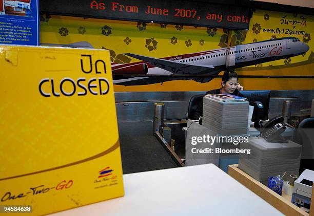 An employee answers phone calls at the closed One Two Go Orient Thai Airways check-in counter at Don Mueang airport in Bangkok, Thailand on Sunday,...