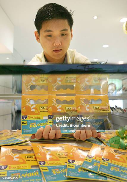 An employee displays Digi.Com Bhd.'s prepaid cards at the company's service center in Shah Alam, Selangor, Malaysia, on Tuesday, Oct. 16, 2007....