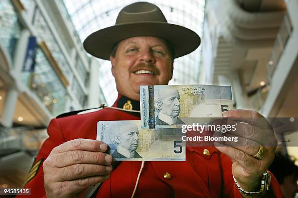 Sgt. Moshe Gordon, head of the force's anti counterfeiting force in Ontario, holds up the new $5 dollar Canadian bill, right, along with the old bill...
