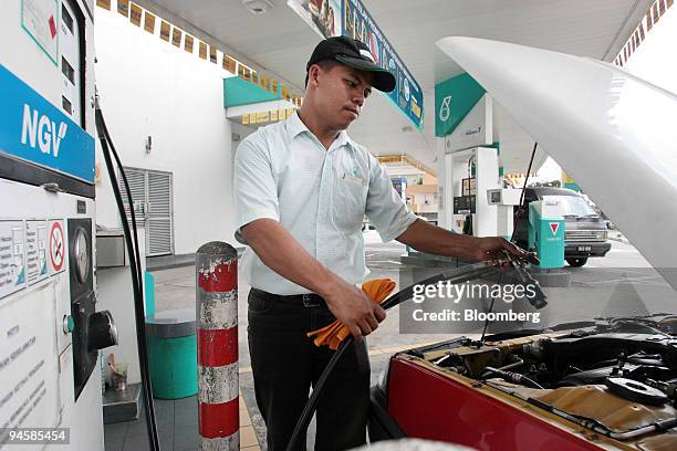 Attendant fills up a taxi with natural gas at a Petronas Gas Bhd. Gas station in Subang Jaya, Malaysia on Wednesday, Jan. 31. 2007.