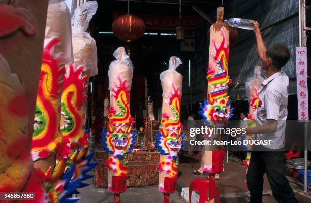 Lighting large sticks of incense offered to ghosts at the Chinese festival of hungry ghosts. Allumage des poteaux d'encens offerts aux fant?mes...