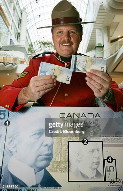 Royal Canadian Mounted Police Sgt. Moshe Gordon, head of the force's anti counterfeiting force in Ontario, holds up the new $5 dollar Canadian bill,...