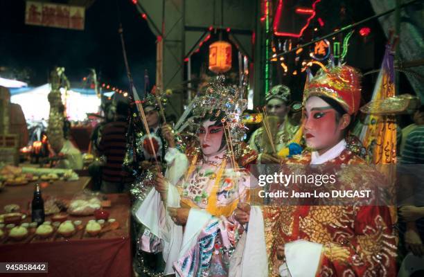 Opera actors holding incense sticks during the Chinese festival of hungry ghosts. Acteurs d'op?ra munis d'encens pendant le festival chinois des...