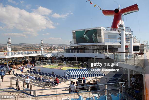 Guests sit on the deck of the Carnival cruise ship "Freedom" while docked at the port of Civitavecchia, Italy, on Tuesday, Oct. 16, 2007. Carnival...