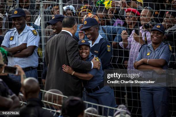 Reverend Jesse Jackson hugs a police officer before the body of Winnie Mandela arrived home in Soweto the day before the funeral for the...