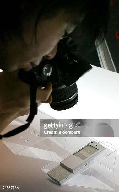Journalist takes a photo of a NTT DoCoMo Inc. New FOMA 704i mobile phone during the launch in Tokyo, Japan, on Wednesday, July 4, 2007. NTT DoCoMo...