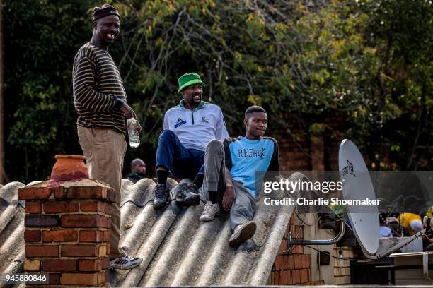People watch from roof tops as the body of Winnie Mandela is returned to her home in Soweto the day before the funeral for the anti-apartheid icon on...