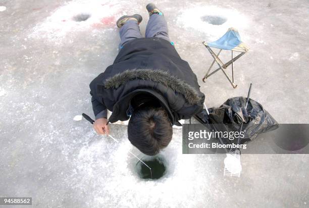 Man looks down an ice hole while fishing for sancheoneo during Hwacheon Sancheoneo Ice Festival 2007, in Hwacheon, South Korea, on Saturday, Jan. 27,...