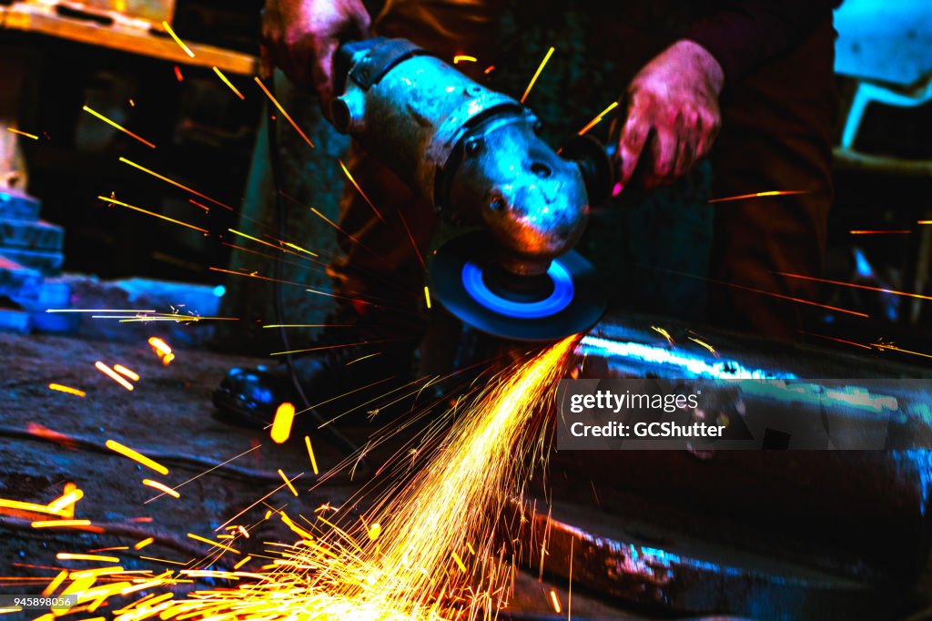 Trabalhador de indústria siderúrgica moagem com cuidado a borda de metal