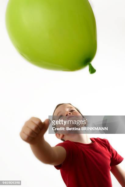 Un garcon de 7 ans donne un coup de poing dans un ballon de baudruche.
