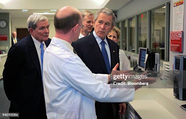 President George W. Bush, right, listens to Dr. Jim Hart, D.O, left, in the emergency room unit at St. Luke's East Health Systems hospital in Lee's...