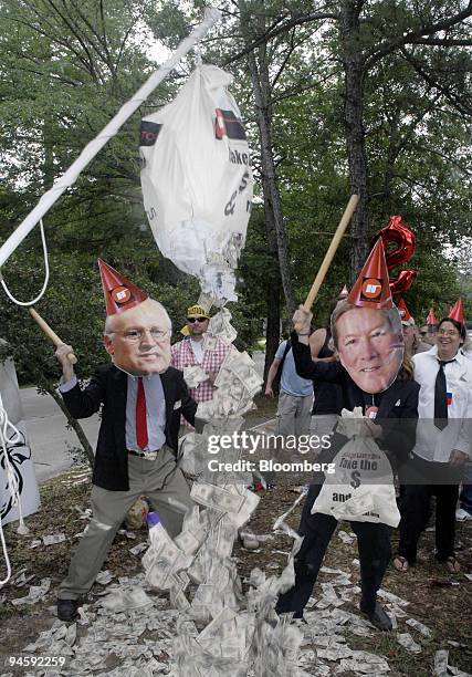 Masked characters depicting U.S. Vice President Dick Cheney, left, and Halliburton's chief executive officer, Dave Lesar, break a pinata full of...