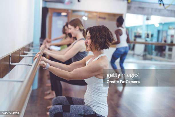 multiethnic group of women do a barre workout together in a modern health club - pike position stock pictures, royalty-free photos & images