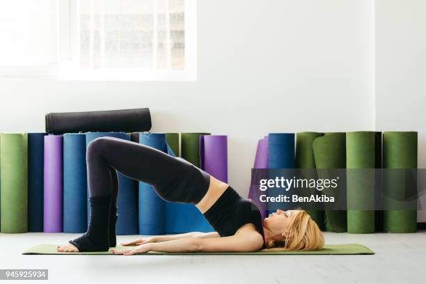young woman practicing yoga in a fitness studio, setu bandha sarvangasana. - setu bandha sarvangasana stock pictures, royalty-free photos & images