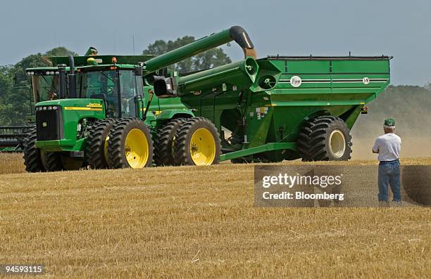 Neighbor watches as a farmer uses new equipment to cut his first day harvest of more than 900 acres of winter wheat in a field near Delaware, Ohio,...