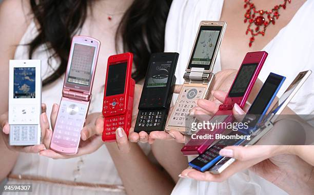 Models display NTT DoCoMo Inc.'s new FOMA 704i series mobile phones during the launch in Tokyo, Japan, on Wednesday, July 4, 2007. Acca Networks Co....