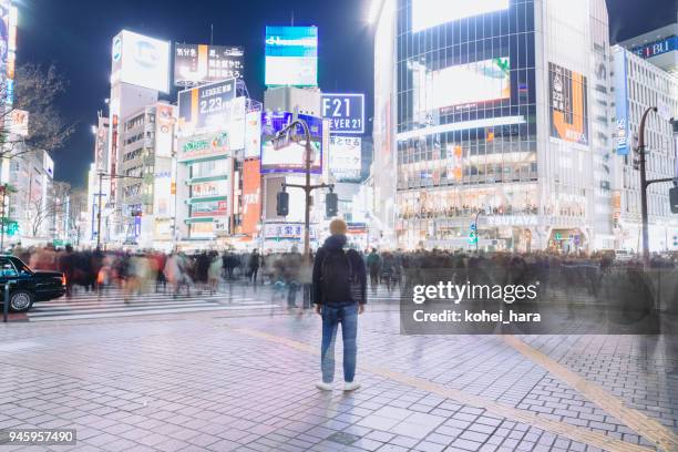 un turista en el cruce de shibuya por la noche - distrito de shibuya fotografías e imágenes de stock