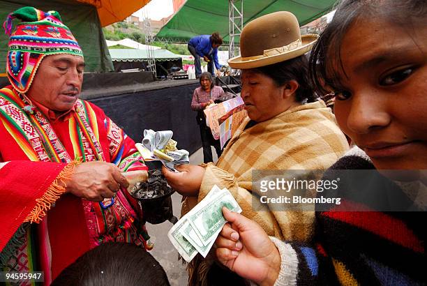 Bolivian women make blessings on reproductions of U.S. Dollars by a local Witch during the Alasita festival in La Paz, Bolivia, on Wednesday, January...
