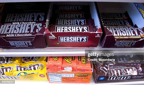 Hershey's Milk Chocolate bars and Reese's Pieces, top and center, sit on a shelf alongside bags of M&Ms, a Mars product, at Montrose Spa in...