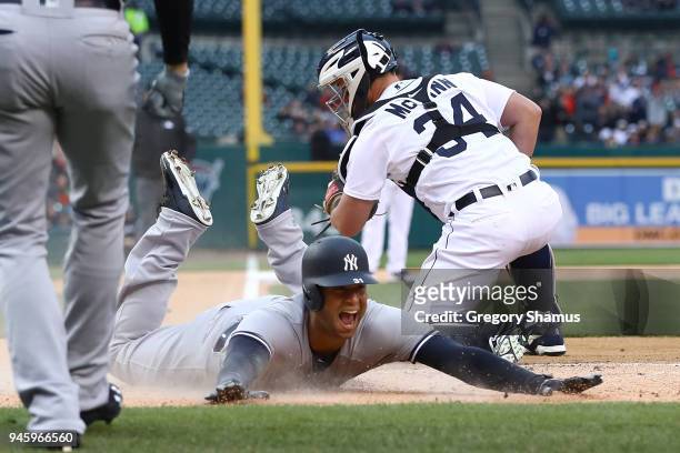 Aaron Hicks of the New York Yankees slides into home plate next to James McCann of the Detroit Tigers for a second inning inside the park home run at...