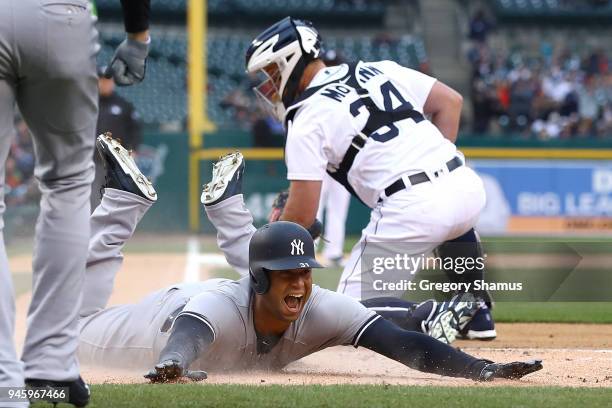 Aaron Hicks of the New York Yankees slides into home plate next to James McCann of the Detroit Tigers for a second inning inside the park home run at...