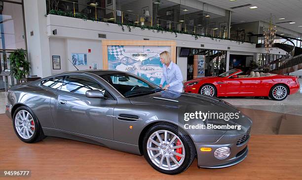 Aston Martin of Palm Beach sales associate Patricia Romeo does a final check on an Aston Martin Vanquish S coupe, which retails for $268 foreground,...