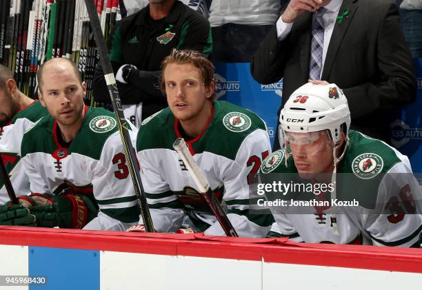 Nate Prosser, Jonas Brodin and Nick Seeler of the Minnesota Wild look on from the bench prior to puck drop against the Winnipeg Jets in Game Two of...