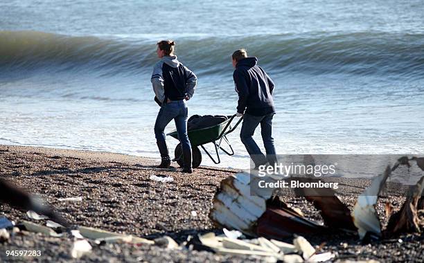 Members of the public scavenge wreckage from the stricken ship the MSC Napoli seen off the coast at Branscombe in Devon, UK, Tuesday, Jan. 23 2007.