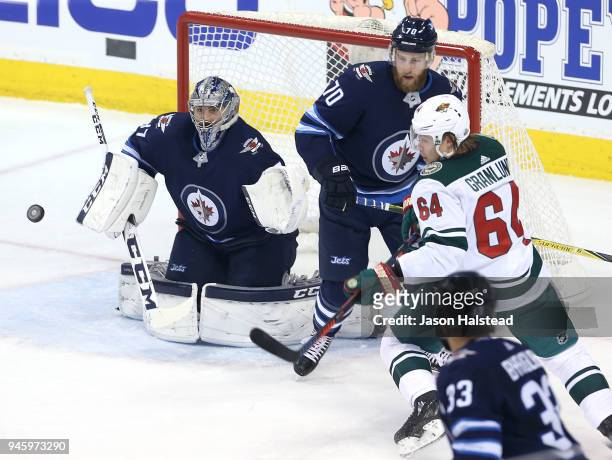 Mikael Granlund of the Minnesota Wild looks for a rebound in front of Connor Hellebuyck and Joe Morrow of the Winnipeg Jets in Game Two of the...