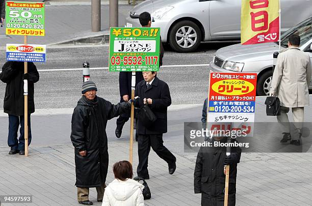 Day laborers stand with sign boards in front of a railway station exit in Tokyo, on Wednesday, Jan. 24, 2007. Day laborers act as human sign boards,...