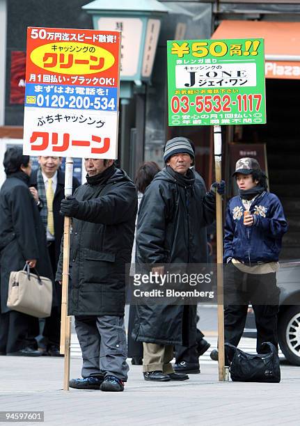 Day laborers stand with sign boards in front of a railway station exit in Tokyo, on Wednesday, Jan. 24, 2007. Day laborers act as human sign boards,...