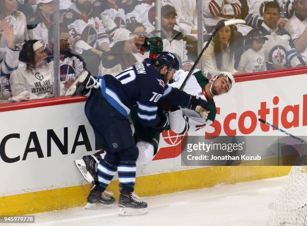 Joe Morrow of the Winnipeg Jets lays a check on Jordan Greenway of the Minnesota Wild along the boards during second period action in Game Two of the...