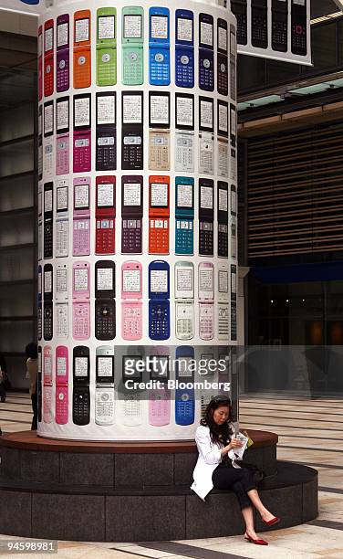 Woman sits by a Softbank Corp. Mobile phone advertising display in Tokyo, Japan, on Monday, May 7, 2007. Softbank Corp., Japan's third-biggest...