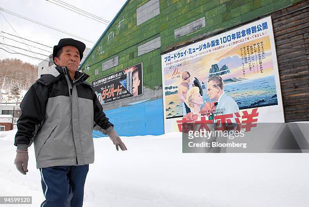 Resident walks past a building with posters for the films "Die Hard" and "South Pacific" in Yubari, Japan, on Tuesday, Mar. 13, 2007. Yubari, a...