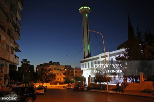 Photo taken in the early hours of April 14, 2018 shows two men walking past a mosque before the daybreak Muslim prayer in Damascus' Mazze...