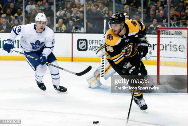 Boston Bruins right defenseman Kevan Miller looks to clear the puck with ]Toronto Maple Leafs left wing James van Riemsdyk in tow during Game 1 of...