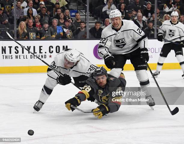 William Carrier of the Vegas Golden Knights tries to stay with the puck as he gets knocked down by Paul LaDue and Trevor Lewis of the Los Angeles...