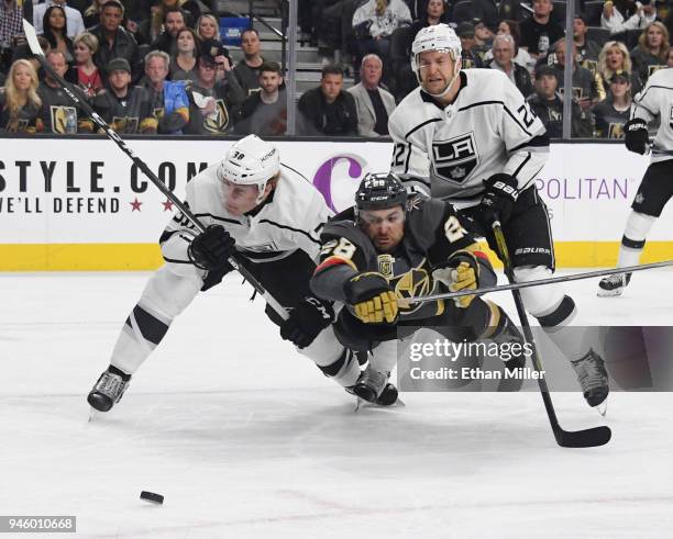 William Carrier of the Vegas Golden Knights tries to stay with the puck as he gets knocked down by Paul LaDue and Trevor Lewis of the Los Angeles...