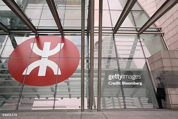 Man talks on the phone and smokes a cigarette in front of the MTR Corp. Logo at Hong Kong Station, in Hong Kong, China, on Tuesday, March 13, 2007....
