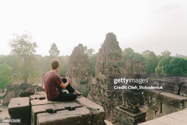 mann sitzt im tempel von angkor in kambodscha - angkor wat stock-fotos und bilder