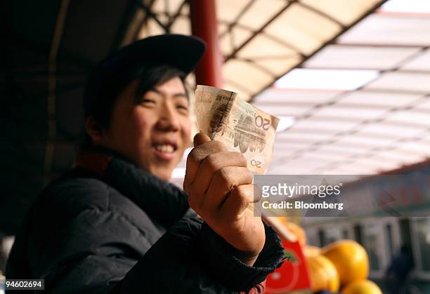 Fruit seller holds up a 20 yuan note in Beijing, China, on Tuesday, Jan. 8, 2008. Like it or not, China has no choice other than to let the yuan...