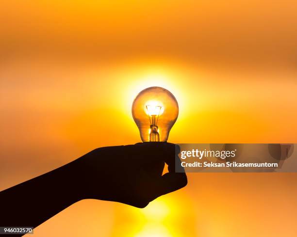 hand holding a light bulb at sunset - chanthaburi sea fotografías e imágenes de stock