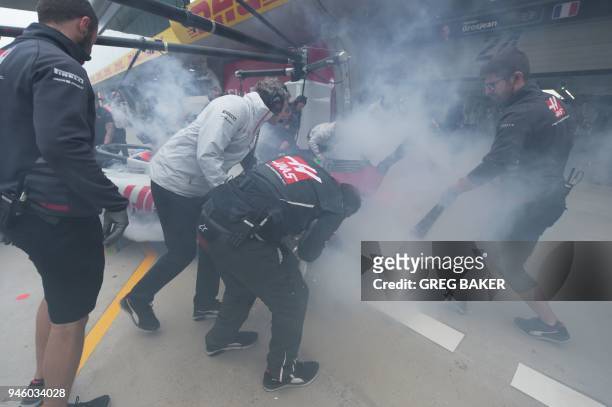 Haas F1 mechanics use extinguishers on the car of French driver Romain Grosjean in the pits during a practice session for the Formula One Chinese...