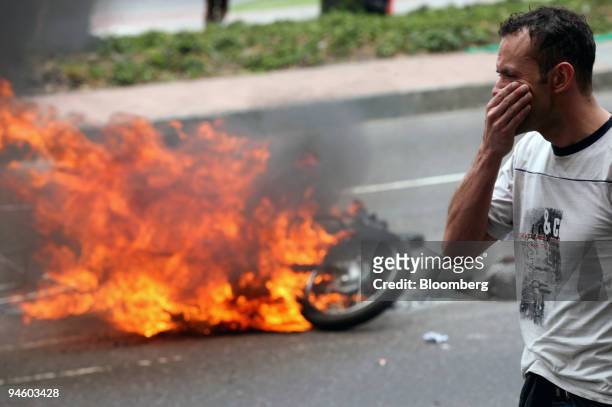 Protestor covers his face as a motorcycle burns in the background during a protest in Bogota, Colombia on Sunday, March 11, 2007. Protests turned...