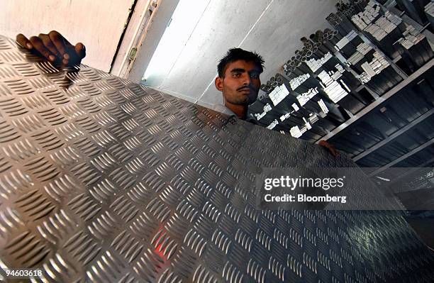 Metal shop employee stands beside an aluminium sheet in Mumbai, on Saturday, Jan. 20, 2007. Hindalco Industries Ltd., a leading manufacturer of...